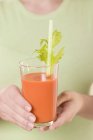 Femme tenant un verre de jus de carotte — Photo de stock