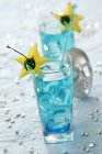 Closeup view of Blue Lagoon cocktails with starfruit slices and cherries — Stock Photo