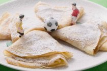 Closeup view of crepes with icing sugar, football figures and football — Stock Photo
