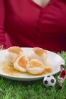 Woman serving apricot dumplings with football figure and football in hands, midsection — Stock Photo