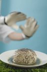 Closeup view of yeast dumpling with poppy seeds and footballer hands on background — Stock Photo