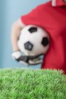 Vue recadrée de l'homme tenant le football derrière le gazon artificiel — Photo de stock