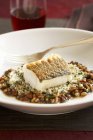 Baked Cod over Beans on white plate with fork — Stock Photo