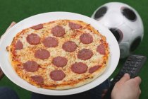 Männliche Hand hält Teller mit Pizza — Stockfoto