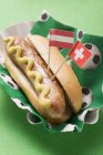 Hot dog with mustard and flags — Stock Photo