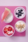 Cuatro yogures con bayas y cereales - foto de stock