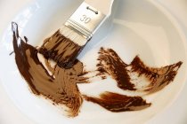 Closeup view of brush with chocolate in white dish — Stock Photo