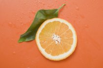 Rebanada de naranja con hoja - foto de stock