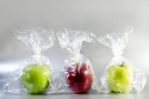 Três maçãs em sacos de plástico — Fotografia de Stock