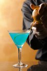 Крупный план бармена, добавляющего апельсиновый корневой гарнир в синий коктейль — стоковое фото