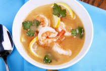 Vue rapprochée sur le dessus de la soupe au citron et aux crevettes avec coriandre dans un bol — Photo de stock
