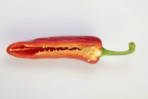 Piment cru rouge coupé en deux sur la surface blanche — Photo de stock