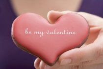 Closeup cropped view of hand holding a Valentine Day biscuit — Stock Photo