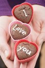 Closeup cropped view of hands holding chocolate buns for Valentine Day — Stock Photo