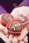 Closeup cropped view of hands holding chocolate buns for Valentine Day — Stock Photo
