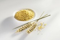 Bulgur in small dish and wheat spikelets — Stock Photo