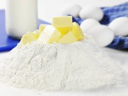 Closeup view of flour heap with cubes of butter — Stock Photo