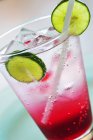 Closeup view of raspberry soda with ice cubes and lime slices in glass — Stock Photo