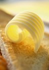 Closeup view of butter curl on toast — Stock Photo