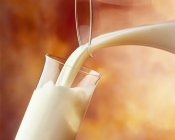 Наливая стакан молока — стоковое фото