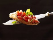 Closeup view of Bruschetta with herb on a knife — Stock Photo