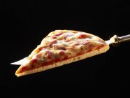 Slice of pizza on knife — Stock Photo