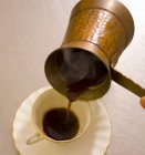 Verter el café turco en la taza - foto de stock