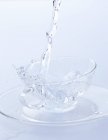 Наливание воды в стеклянную чашку — стоковое фото