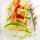 Prawn, lime and tomato skewer on white plate — Stock Photo