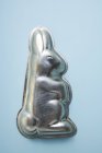 Вид крупным планом одного пасхального кролика, выпекающего олово на голубой поверхности — стоковое фото