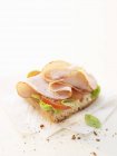 Smoked chicken breast on baguette laying  on paper napkin on white background — Stock Photo