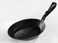 Closeup view of iron frying pan on white surface — Stock Photo