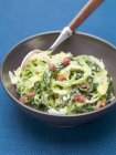 Savoy cabbage with bacon on black plate over blue surface — Stock Photo
