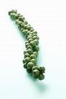 Closeup view of green peppercorns cluster on white surface — Stock Photo