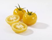 Целые и пополам желтые помидоры — стоковое фото