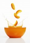 Apricot slices falling into juice — Stock Photo