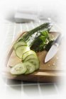 Cucumber, partly sliced, on chopping board, blurred background and foreground — Stock Photo
