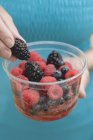Woman holding plastic tub of berries — Stock Photo