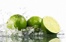 Limes with splashing water — Stock Photo