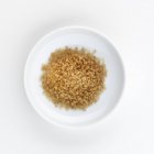 Вид сверху на коричневый тростниковый сахар на белой тарелке — стоковое фото