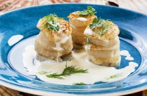 Scallops with artichokes in a cream sauce on blue plate — Stock Photo