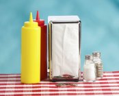 Altmodisches Esstisch-Set mit Ketchup- und Senfflaschen, Taschentüchern, Münzen und Gewürzgussformen — Stockfoto