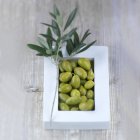 Green olives in white bowl — Stock Photo