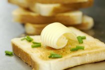 Closeup view of toast with a curl of butter and chives — Stock Photo