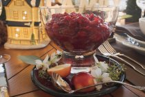 Крупный план клюквенного соуса с яблоком и цветами на рождественском столе — стоковое фото