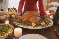 Woman putting turkey on table — Stock Photo