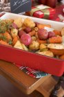 Roasted root vegetables on Christmas table in red dish — Stock Photo