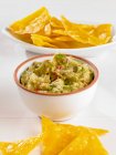 Bowl of Guacamole with Chips on white surface — Stock Photo