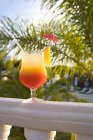Vue diurne du cocktail avec tranche d'orange, paille et parapluie sur la rampe du balcon — Photo de stock