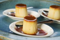 Nahaufnahme von Creme Caramel mit Löffeln auf Tellern — Stockfoto
